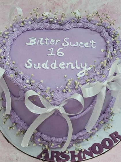 A "Bitter Sweet 16" vintage heart cake. This tall roasted almond chocolate cake is decorated in lilac with delicate piping and white ribbons.