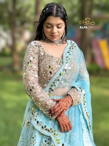 A candid-style shot showing the details of the mirror-work blouse and henna.