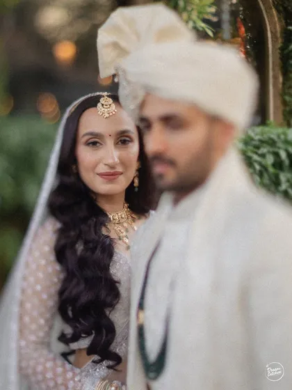 An artistic portrait with the bride in sharp focus and the groom softly blurred, creating a beautiful and romantic composition.