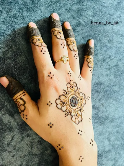 A delicate and symmetrical design with a central floral motif. Small dots and stars are scattered around it, and the fingers have simple flower patterns.