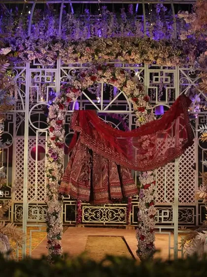An artistic shot of the bride's wedding lehenga hanging against the beautifully decorated mandap before the ceremony begins.