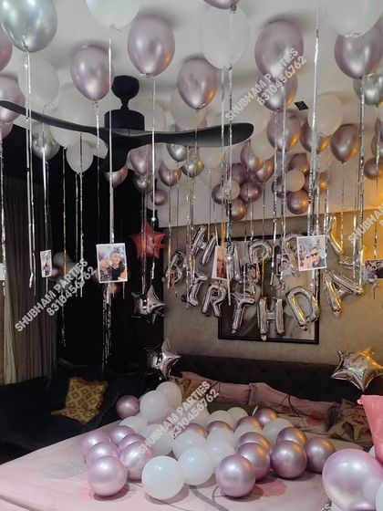 A room filled with chrome and white balloons and hanging photos for a personalized birthday surprise.