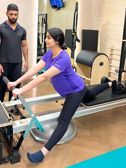 Maintaining flexibility and mobility is a key focus in our prenatal programs. This client performs a gentle stretch on the reformer, helping to alleviate common pregnancy-related discomfort.