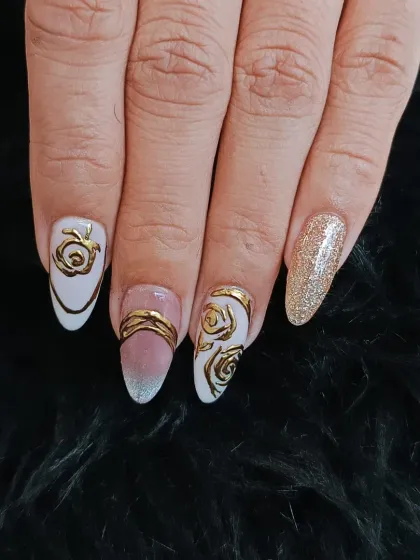 An artistic and elegant design featuring a milky white base with intricate, raised gold chrome rose patterns. A gold glitter accent nail completes this luxurious look.