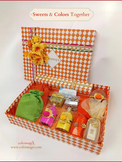 Sweets and colors together. This open view of our checkered Holi hamper reveals the thoughtful curation of colorful bottles, sweet pouches, and other festive items.