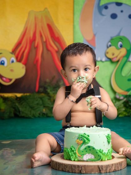 "Hey, it's edible!" This little one, dressed in a smart bow tie, is enjoying his first taste of his dinosaur-themed birthday cake.
