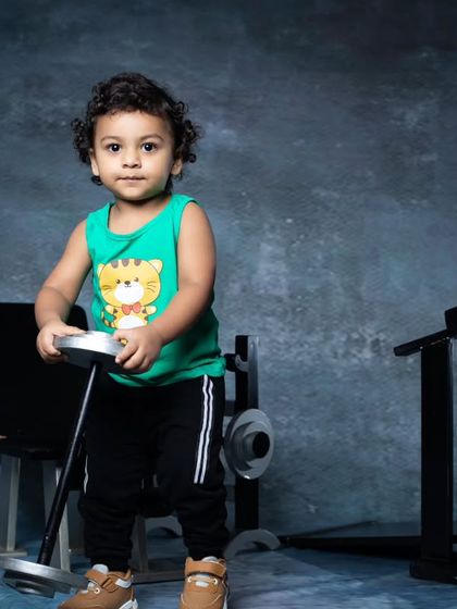 This toddler is testing his strength, lifting a dumbbell in our fully equipped mini gym.