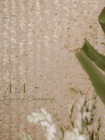 A close-up detail of the floral backdrop from the signing ceremony, showing the texture and delicate nature of the hanging tuberose strings.