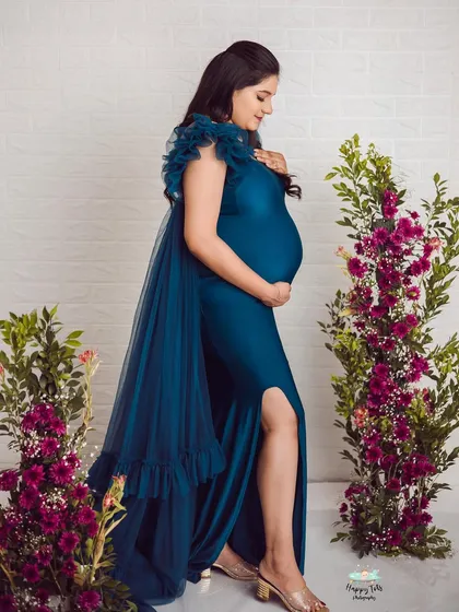 A profile shot of this gorgeous mom-to-be in a deep teal gown. The ruffled shoulder details and cape add a touch of high-fashion drama.