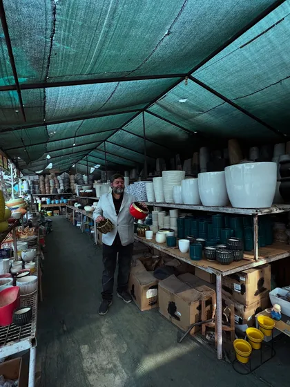 A wide shot of me in our main pot section. You can see the shelves are packed with hundreds of different ceramic pots, giving you an idea of the scale of our collection.