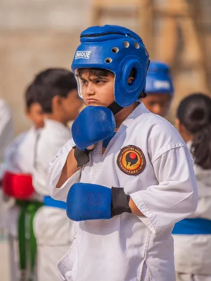 A young competitor, focused and ready for a kumite match. We equip our students, even the youngest ones, with the proper safety gear and the mental fortitude required for competitive sparring.