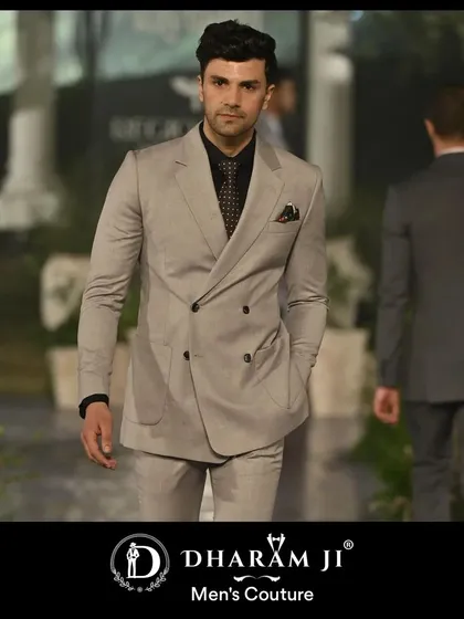 A model on a runway in a light grey double-breasted suit. The cut is classic and powerful, a testament to timeless tailoring.