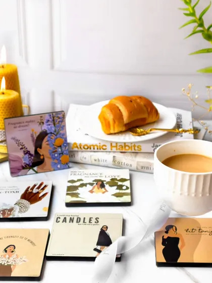A cozy morning scene featuring illustrated cards, a cup of coffee, a croissant, and lit beeswax candles. The warm lighting and lifestyle elements make the products feel part of a beautiful daily ritual.