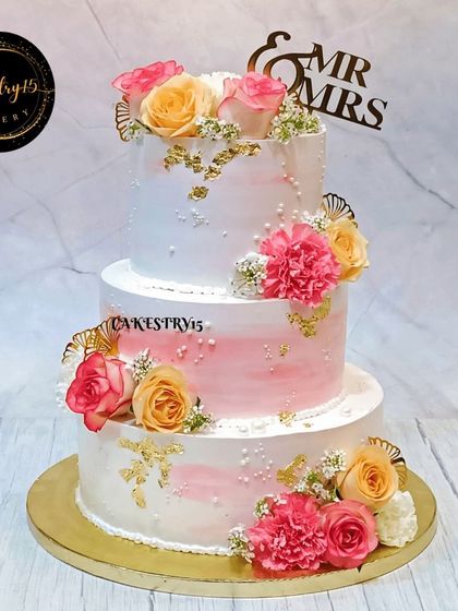 A breathtaking 5kg three-tier engagement cake. This romantic creation features a pink ombre effect and is adorned with real roses, carnations, and gold leaf details.