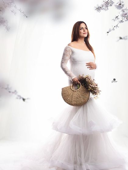 A dreamy and ethereal portrait in a white tiered gown. The soft, out-of-focus floral elements in the foreground and background create a magical, winter-wonderland feel.