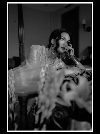 A dramatic black and white portrait for AR by Rhea Kapoor. The composition uses foreground blur and a thoughtful pose to create a classic, cinematic feel.