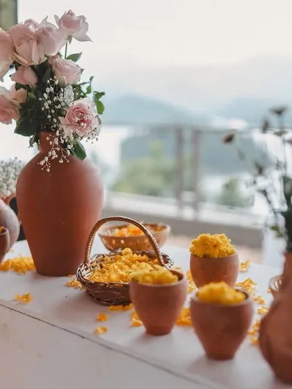Rustic decor details for a Haldi ceremony with a view. We used terracotta pots, wicker baskets, and fresh flowers to create a natural and earthy tablescape that complemented the lakeside setting.