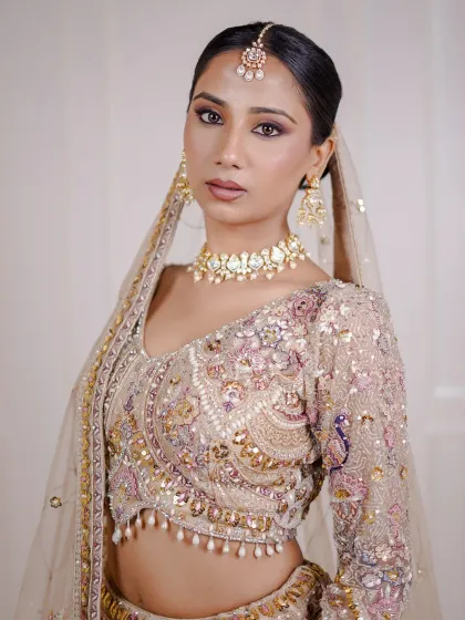 A close-up of a model in our beige and multi-color lehenga. The delicate embroidery and simple jewellery create a very soft and pretty look.