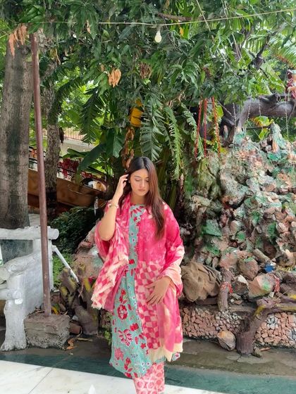 Feeling the Shiv Shakti vibes during the month of Sawan. A full-length shot of me in a pink and blue floral suit in a temple garden.