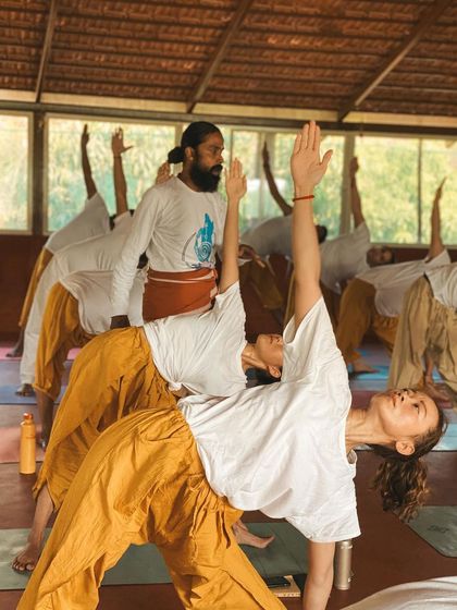 I guide a student in Viparita Virabhadrasana (Reverse Warrior), helping her find length in the side body while staying grounded. These hands-on adjustments are a key part of how we transfer knowledge and feeling.