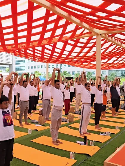 A wide shot of participants at an International Yoga Day event. The collective energy of a large group practicing together creates a powerful and positive atmosphere.