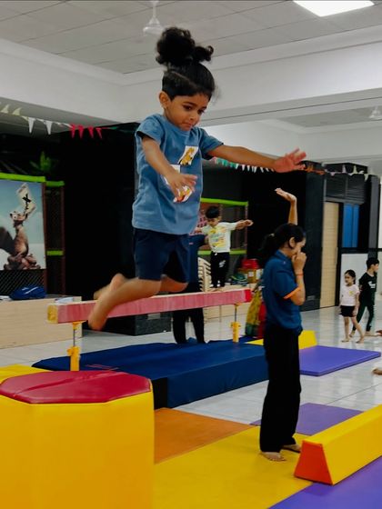 A moment of pure joy and focus as a young student leaps from the balance beam. This activity builds leg strength, spatial awareness, and the courage to take a leap of faith in a controlled setting.