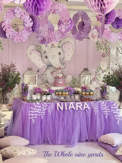 A sweet lavender elephant-themed birthday. The decor featured a custom backdrop with a baby elephant, a tulle table skirt, and low seating for the little guests.