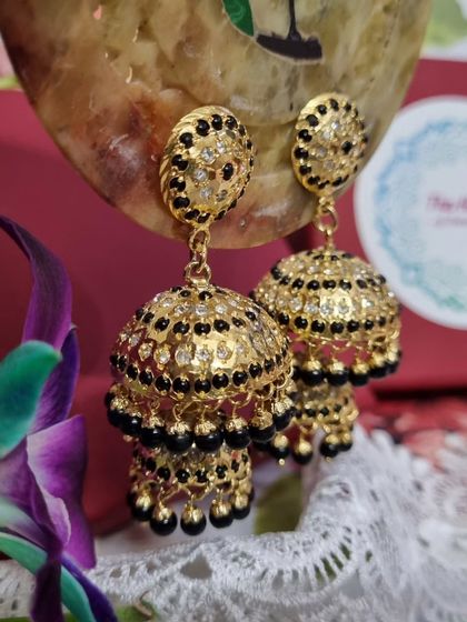 Another view of the 'काजल' (Kajal) jhumkas, highlighting the contrast between the gold plating and the black beads.