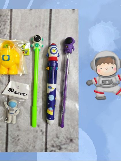 A close-up of the space-themed stationery items, including an astronaut pen, a rocket multi-color pen, and 3D astronaut erasers.