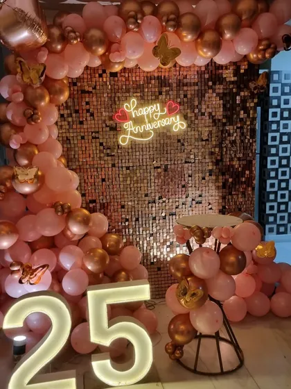 A close-up view of the 25th-anniversary decor, focusing on the texture of the sequin wall and the details of the pink and gold balloon arrangement.