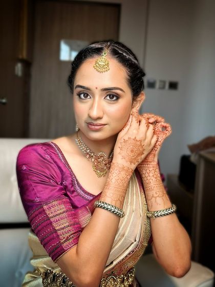 A candid moment of the bride-to-be putting on her earrings, her makeup looking fresh and natural.
