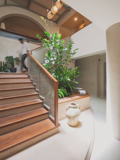 The staircase atrium acts as a modern courtyard, drawing light from above. The design incorporates a planter bed, seamlessly blending architecture, landscape, and interior design to create a refreshing entry experience.