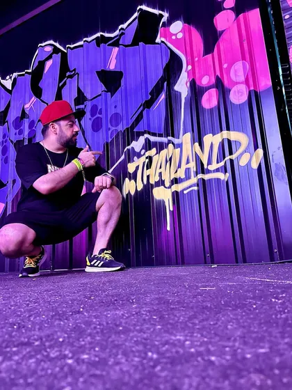 Posing against a vibrant graffiti wall in Thailand. Hip hop culture and art are a huge inspiration.