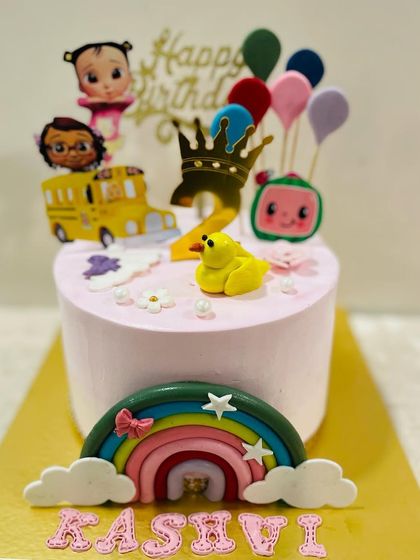 A variation of the pink Cocomelon cake, this one celebrating a second birthday with a crown and colorful balloons.