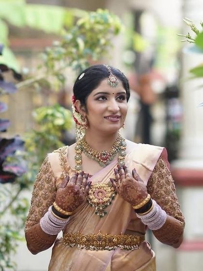 A portrait of the bride, her hands gently framing her face, showcasing the deep color of her henna.