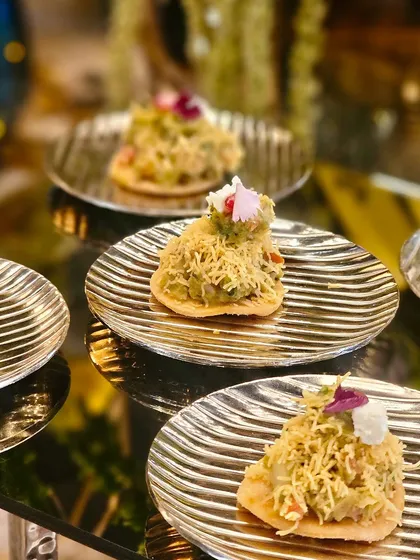 Our modern take on Avocado Papdi Chaat, served on beautiful golden plates, complementing the luxurious setting.