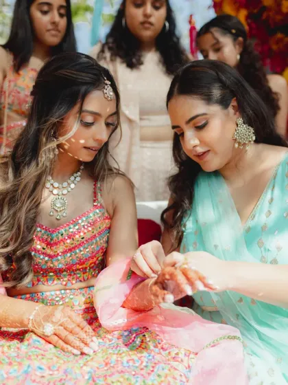 A sister helps the bride with her mehendi. These quiet moments of love and support between family are what make a wedding so special.