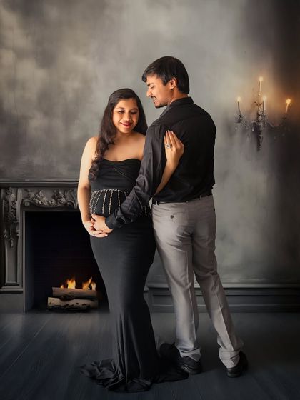 A romantic and cozy indoor portrait. The fireplace and candlelight create a warm, intimate atmosphere for this loving couple's shot.