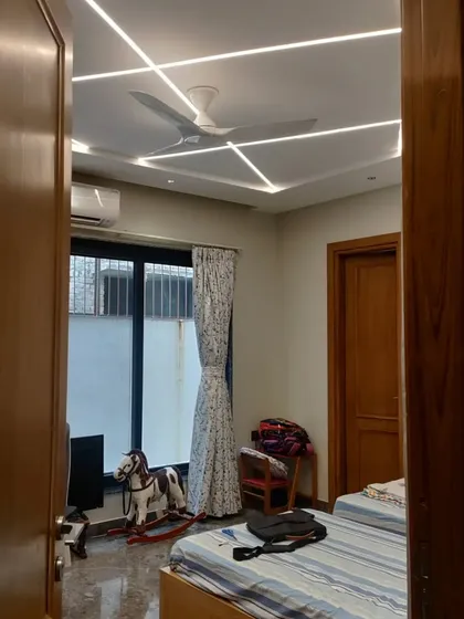A child's bedroom in the Gurgaon residence featuring a unique geometric lighting pattern on the ceiling. The design is playful yet sophisticated, providing a comfortable and well-lit space.