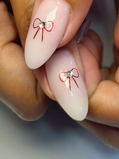 A close-up of the delicate red bow art, finished with a tiny rhinestone for a touch of sparkle.