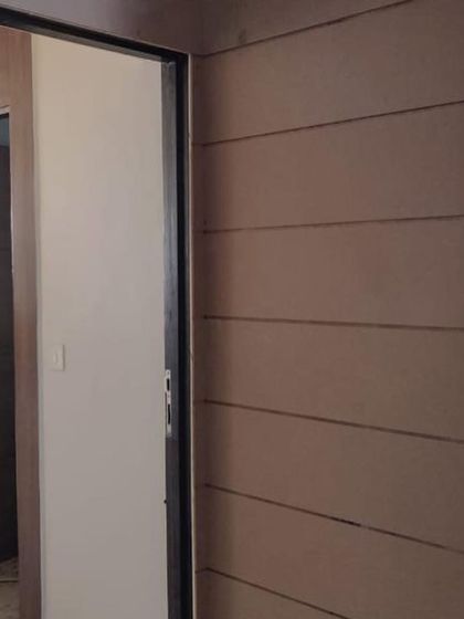 A before-and-after shot of an entrance transformation. The original plain entrance was clad in rich, wood-textured panels to create a warm and inviting first impression.