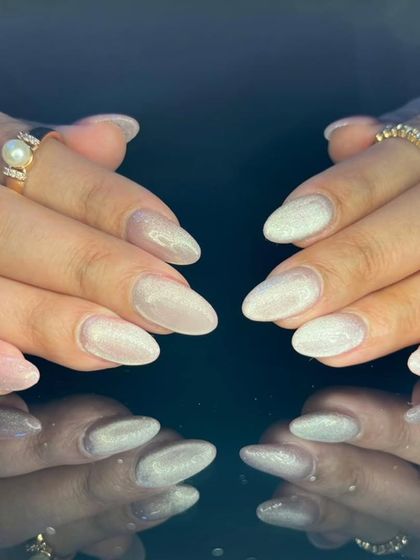 A full set of sparkling white glitter nails on almond-shaped extensions for a frosty, magical look.