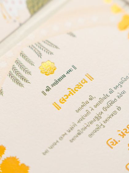 A close-up shot of the gold-foiled Gujarati script on a textured, handmade paper. The combination of the elegant font and the quality of the paper creates a luxurious feel.