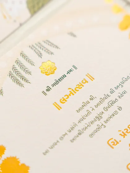 A close-up shot of the gold-foiled Gujarati script on a textured, handmade paper. The combination of the elegant font and the quality of the paper creates a luxurious feel.