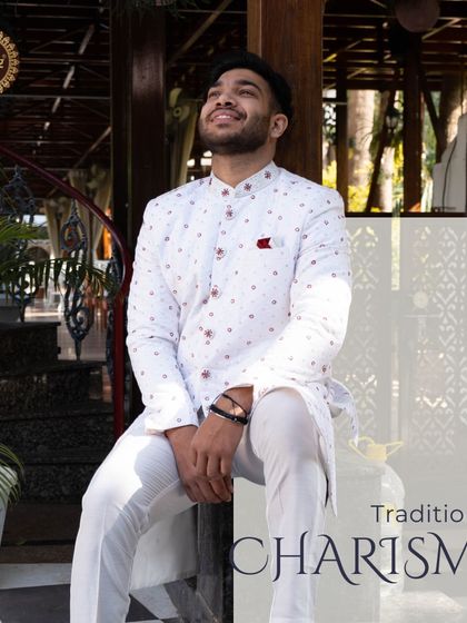 Traditional charisma, redefined. This white sherwani with subtle red motifs offers a fresh and vibrant look for the modern groom.