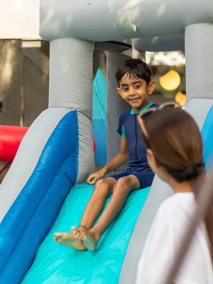 A young boy gets ready at the top of our inflatable water slide, with his mom watching from below. It is a safe and thrilling ride for kids of all ages.