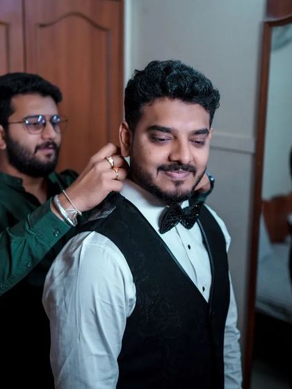 A great getting-ready shot of the groom, with his friend helping him with his bow tie, captured with a cool reflection in the mirror.