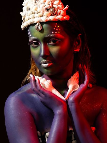 This creative portrait uses body paint and a custom seashell crown to evoke an underwater, mermaid-like theme. The lighting is used to create a deep-sea mood.