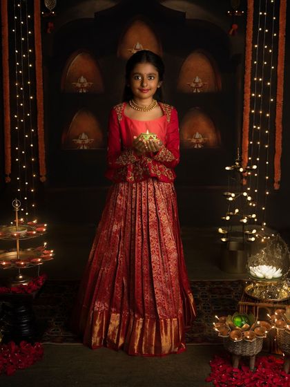 Shubha Deepavali! Holding a diya, this young girl in her beautiful traditional dress embodies the light and grace of the festival of lights.