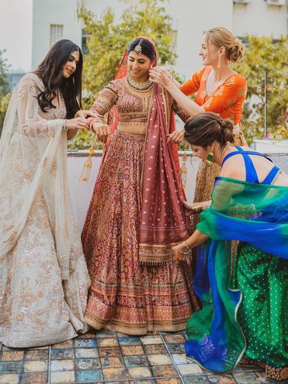 The bride gets help with her dupatta from her international bridesmaids, a moment of friendship and cultural fusion.